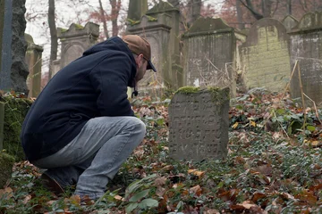 Christian Riemenschneider kniet vor einem Grabstein mit hebräischer Inschrift
